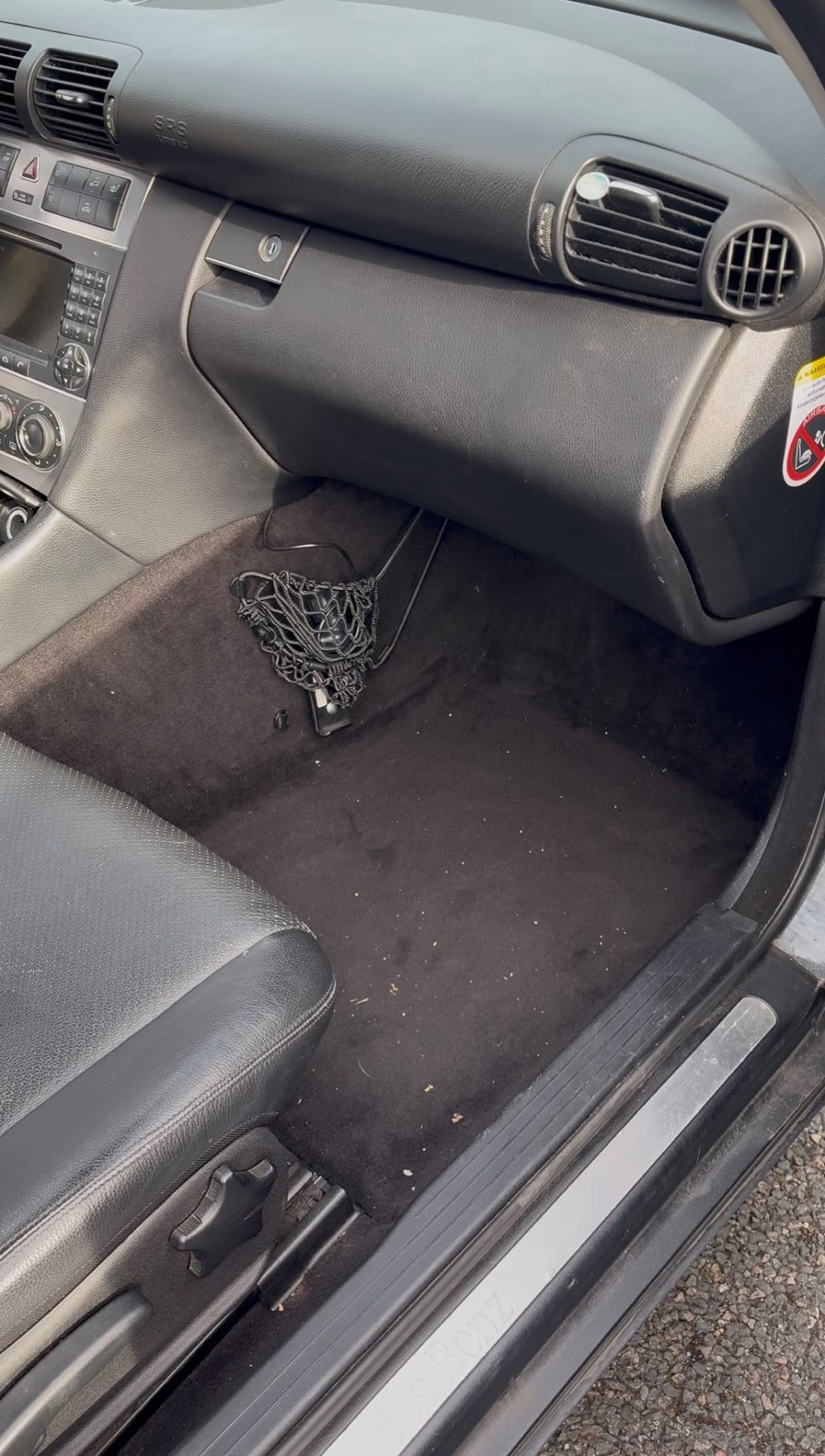 Plancher côté passager d’un véhicule avant le nettoyage : moquette couverte de miettes et de poussière